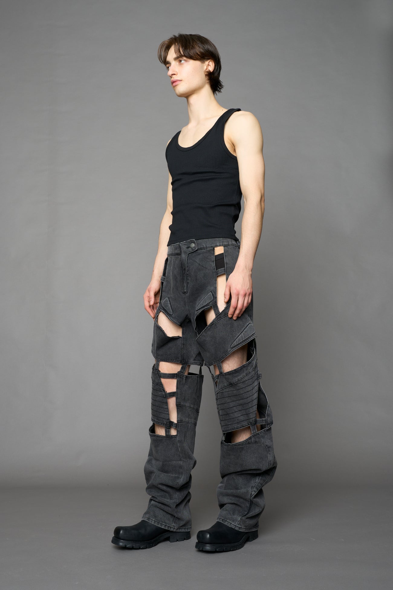 model wearing black washed denim pants with motocross inspired cut outs