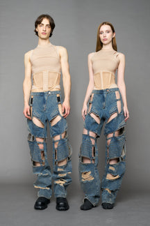 model wearing blue mud denim pants with motocross inspired cut outs