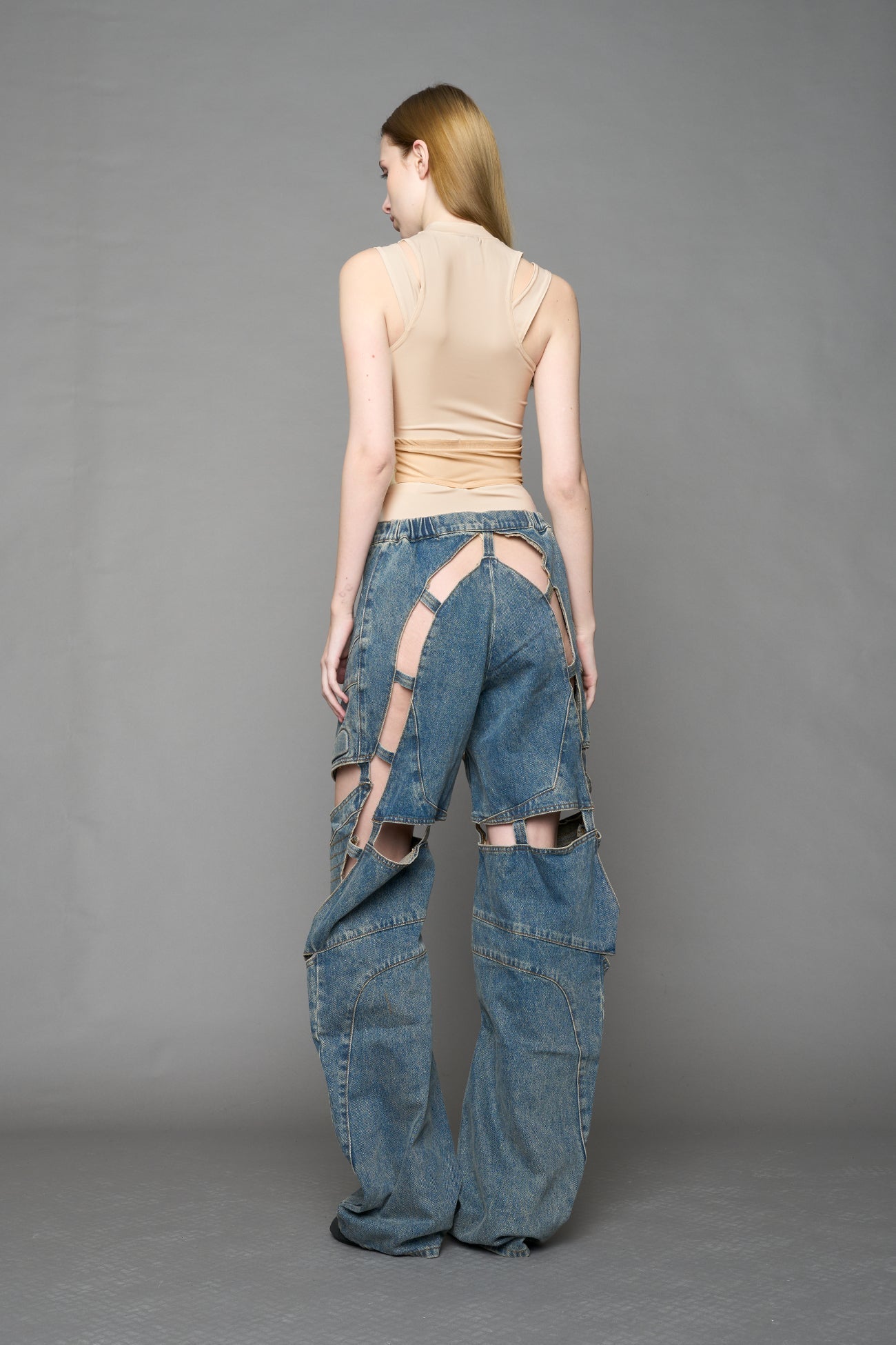model wearing blue mud denim pants with motocross inspired cut outs