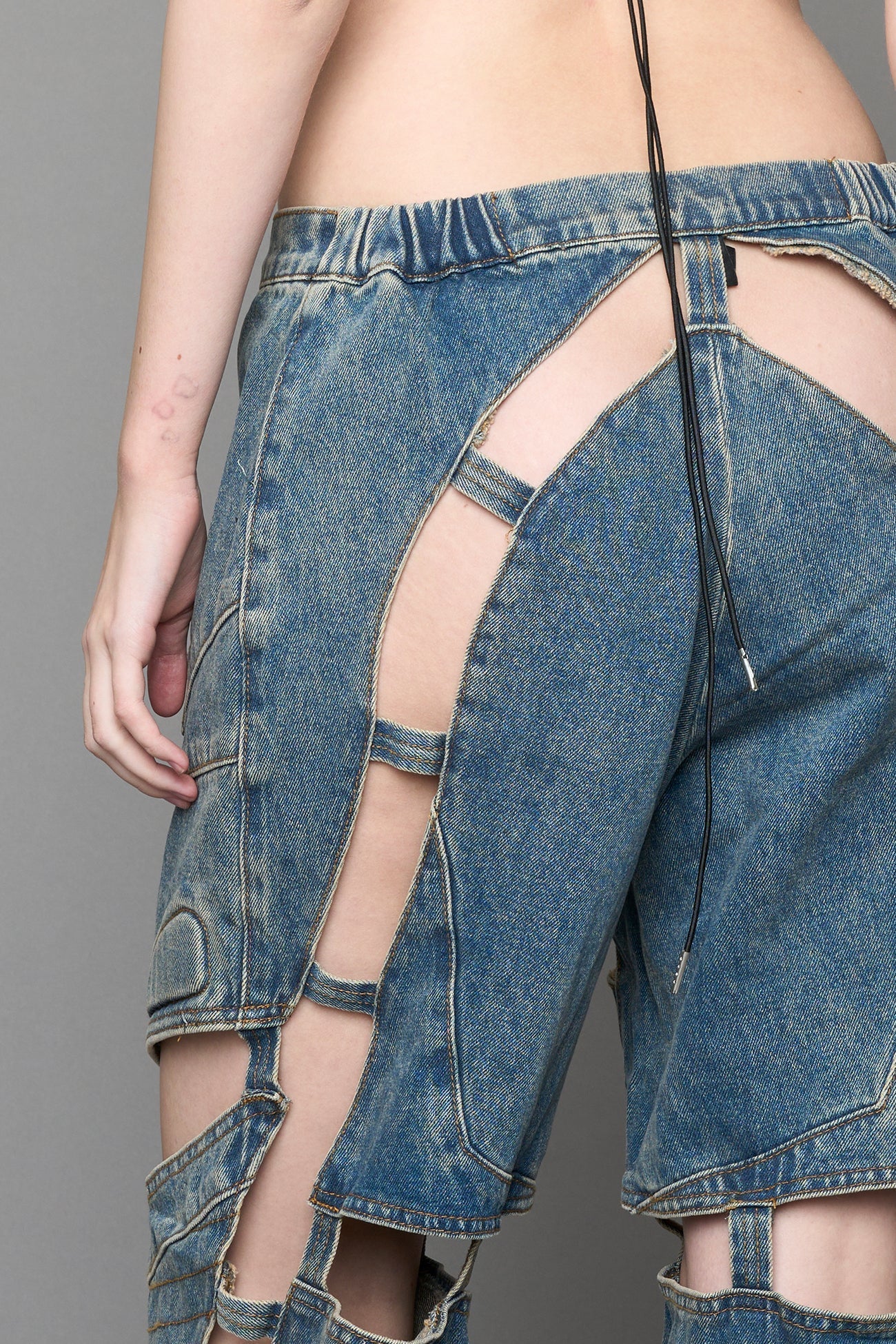 model wearing blue mud denim pants with motocross inspired cut outs