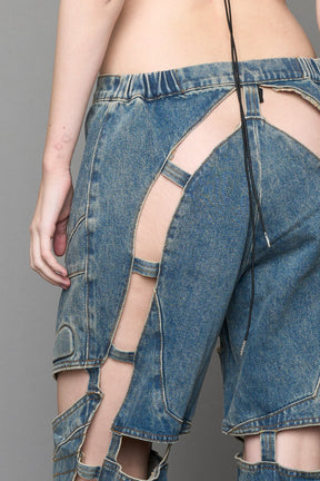 model wearing blue mud denim pants with motocross inspired cut outs