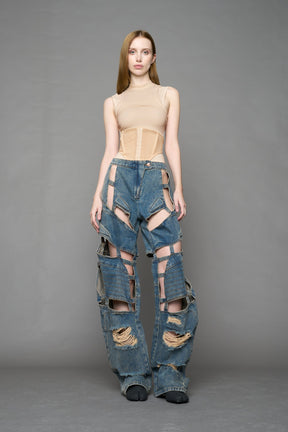 model wearing blue mud denim pants with motocross inspired cut outs