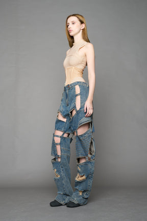 model wearing blue mud denim pants with motocross inspired cut outs