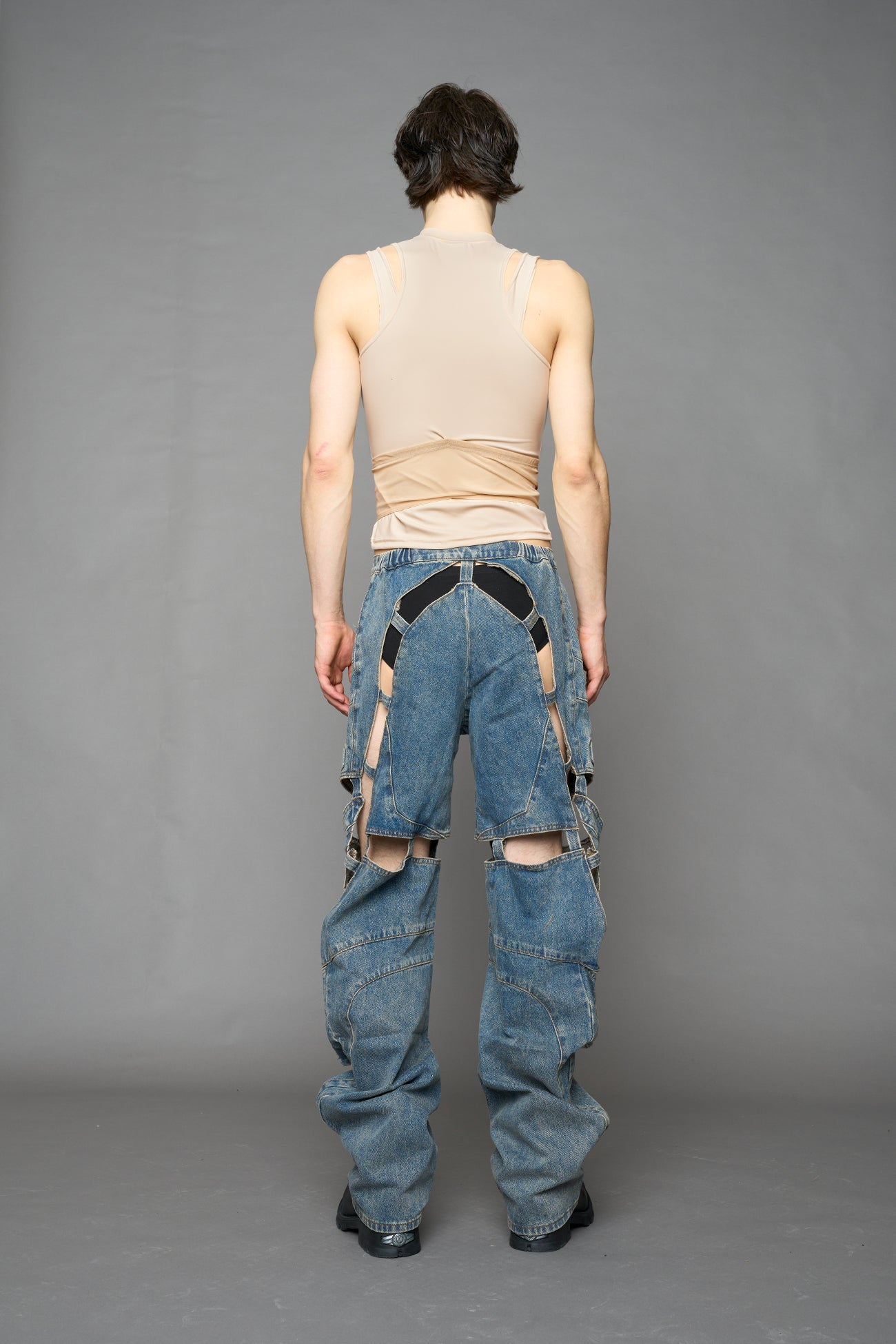 model wearing blue mud denim pants with motocross inspired cut outs