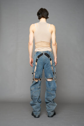 model wearing blue mud denim pants with motocross inspired cut outs