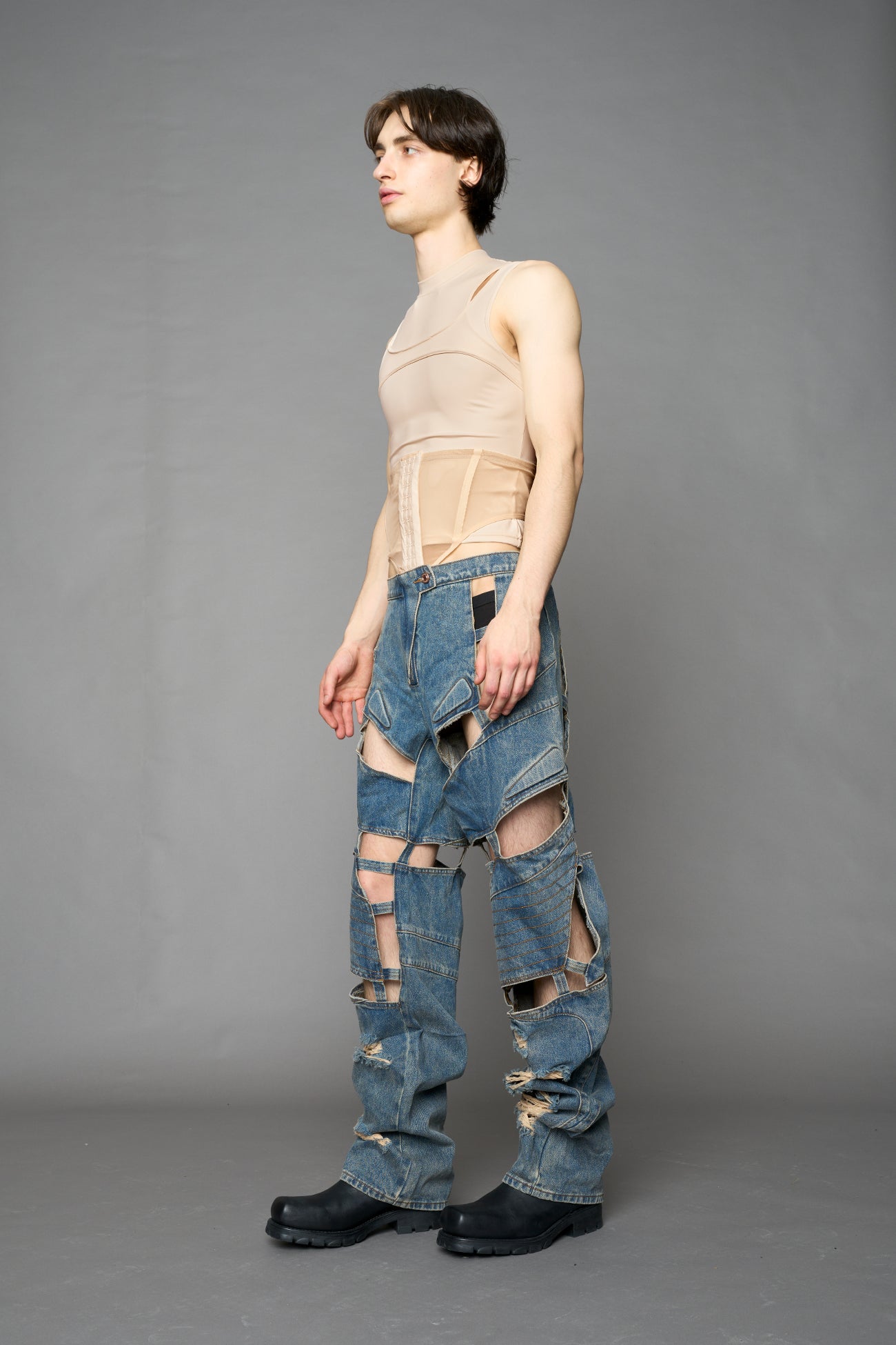 model wearing blue mud denim pants with motocross inspired cut outs