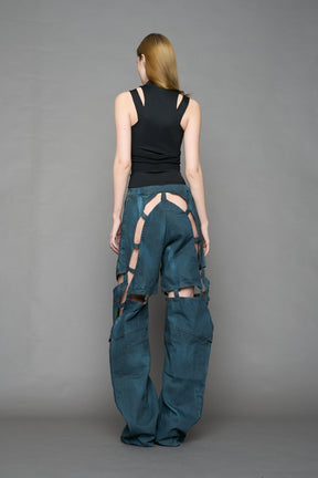 model wearing blue smoke denim pants with motocross inspired cut outs