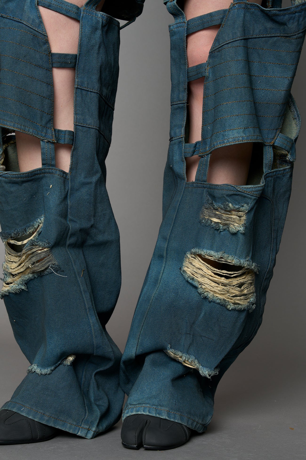 model wearing blue smoke denim pants with motocross inspired cut outs