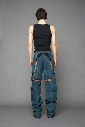 model wearing blue smoke denim pants with motocross inspired cut outs