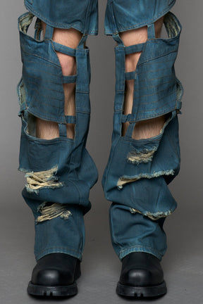 model wearing blue smoke denim pants with motocross inspired cut outs