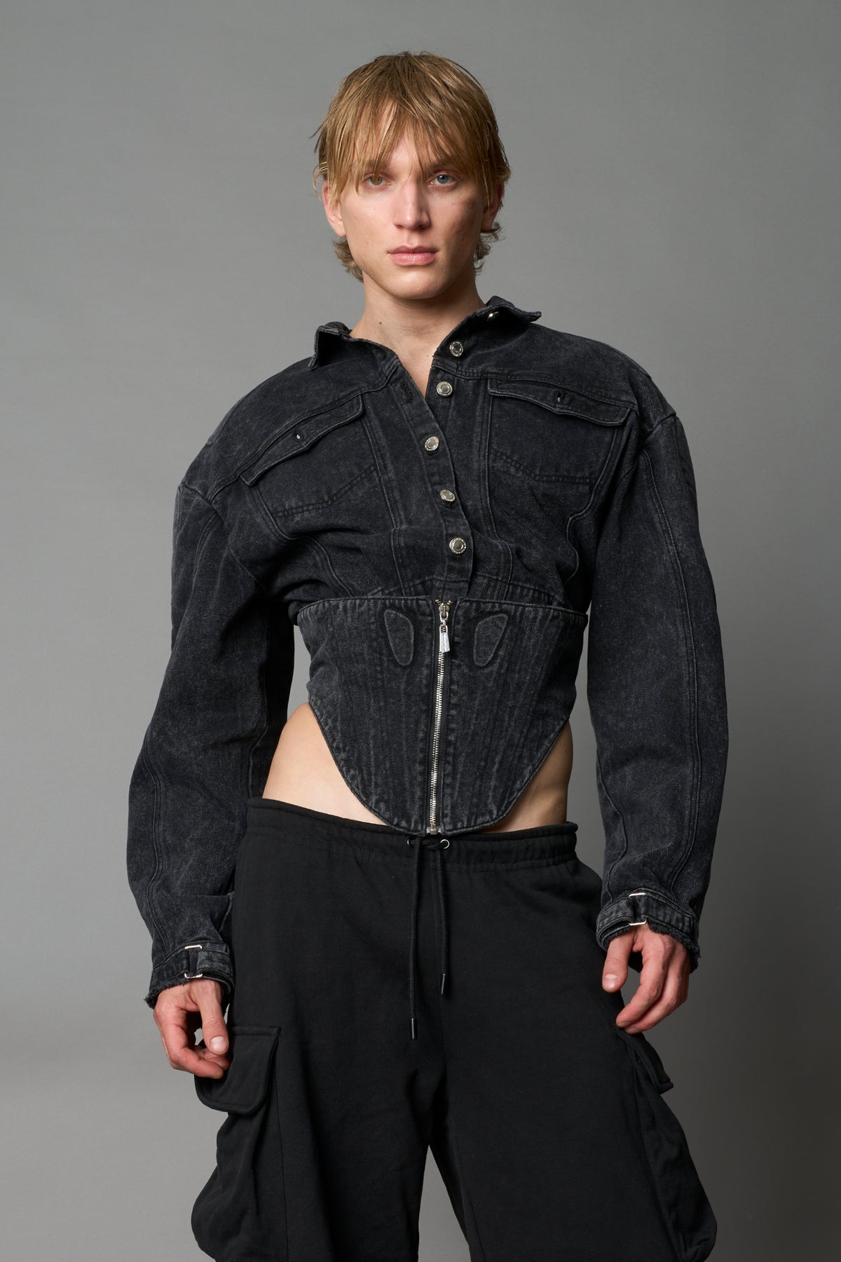 model wearing black washed denim jacket with structured corset waist and moto-style silhouette