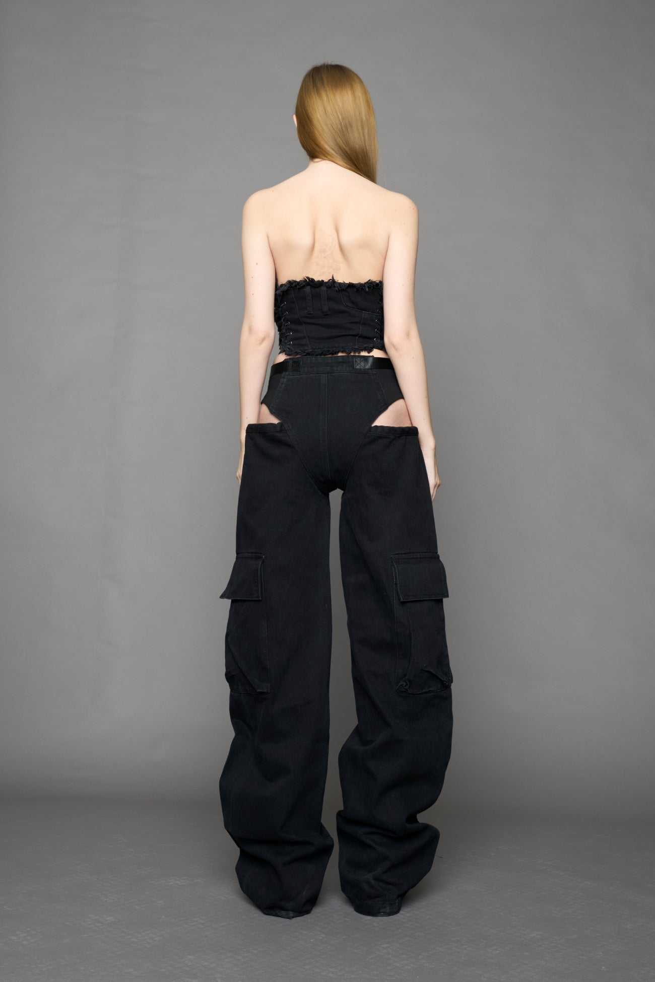 model wearing black dark washed denim trousers with cut out design and 3D pockets