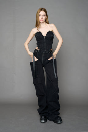 Black dark washed denim cone corset by NAMILIA with spiral-stitched cone cups, strapless fitted silhouette, front zip closure, lace-up sides, and raw frayed edges, worn by model on neutral background.