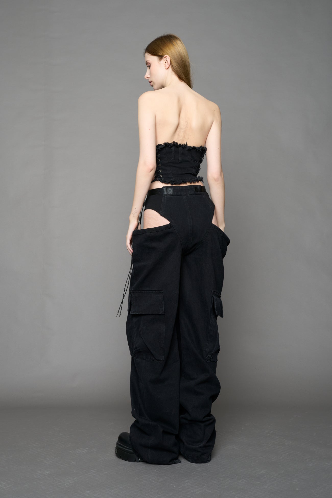 model wearing black dark washed denim trousers with cut out design and 3D pockets