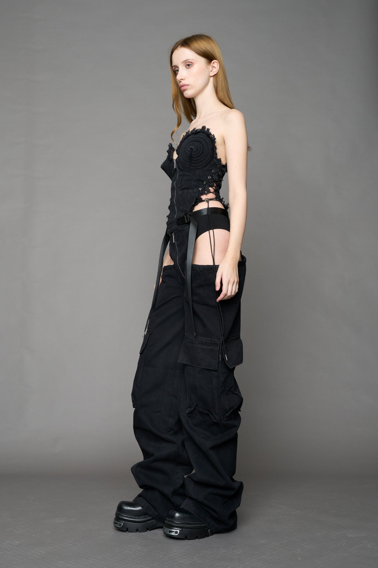 model wearing black dark washed denim trousers with cut out design and 3D pockets