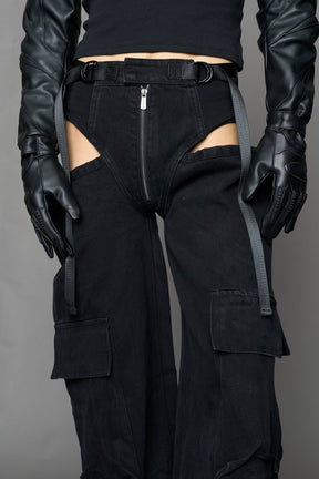 model wearing black dark washed denim trousers with cut out design and 3D pockets
