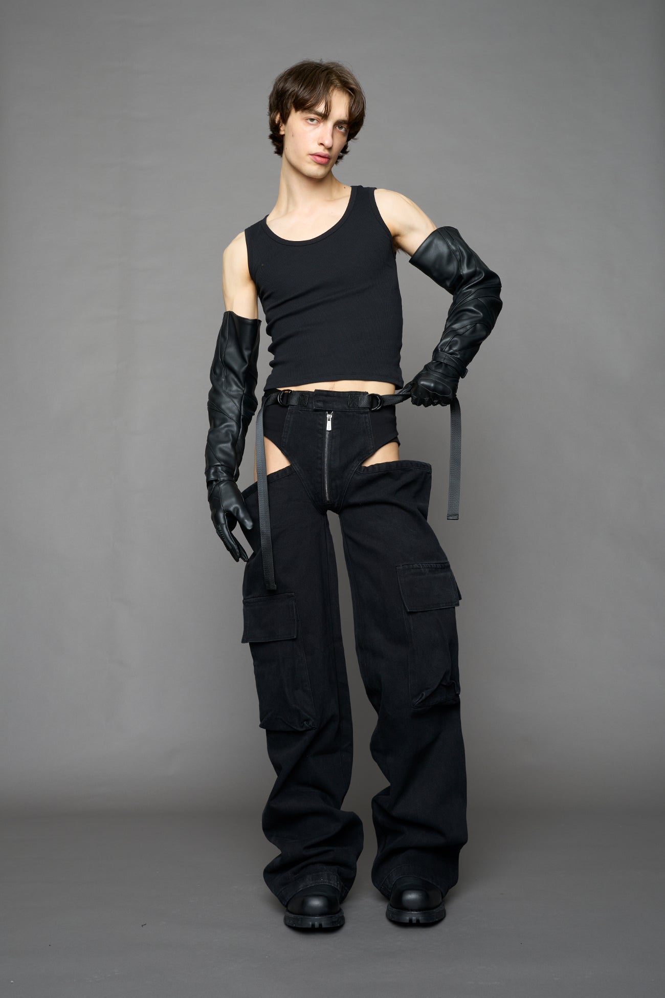 model wearing black dark washed denim trousers with cut out design and 3D pockets