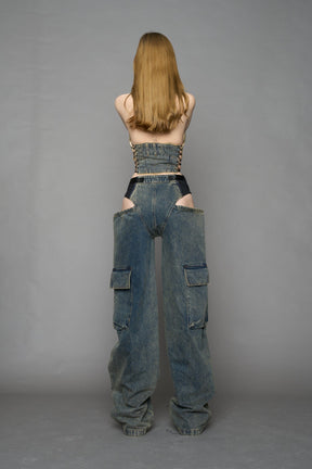 model wearing blue mud washed denim trousers with cut out design and 3D pockets