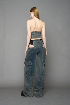 blue mud washed denim cone corset by NAMILIA with spiral-stitched cone cups, strapless fitted silhouette, front zip closure, lace-up sides, and raw frayed edges, worn by model on neutral background.