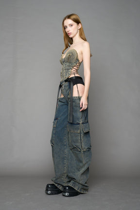 model wearing blue mud washed denim trousers with cut out design and 3D pockets