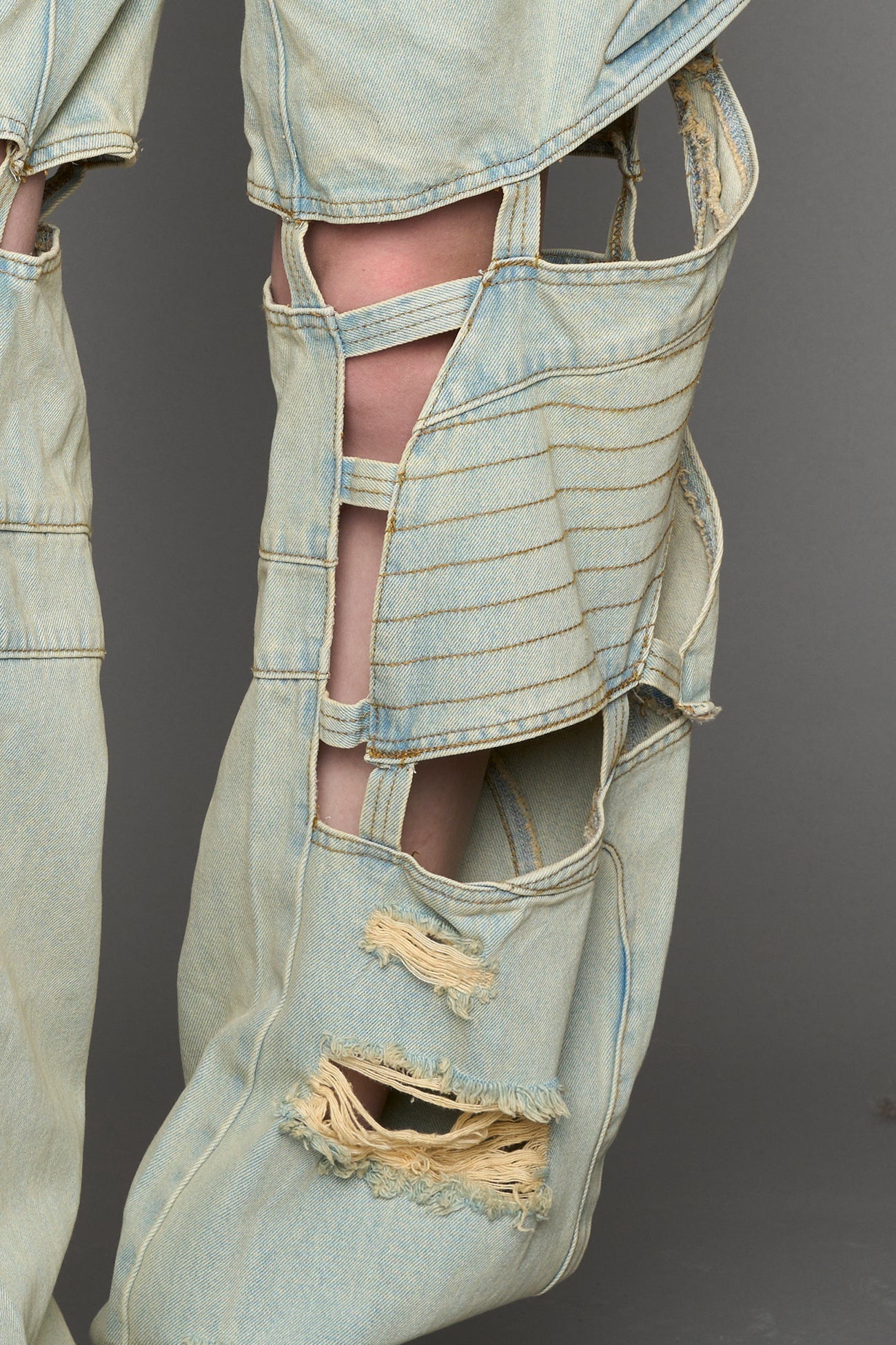 model wearing blue light wash denim pants with motocross inspired cut outs