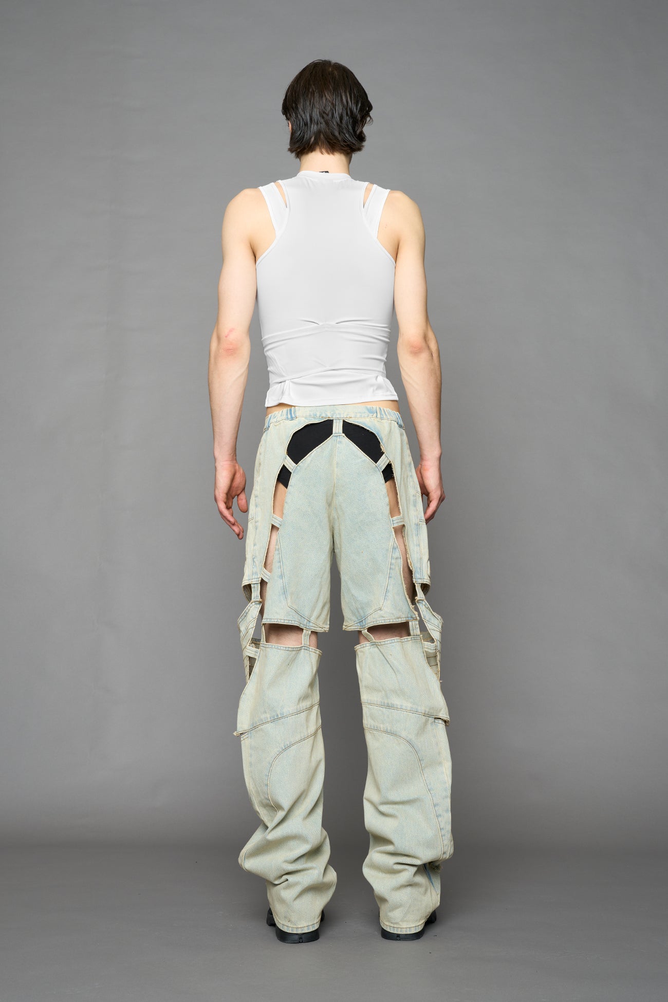 model wearing blue light wash denim pants with motocross inspired cut outs