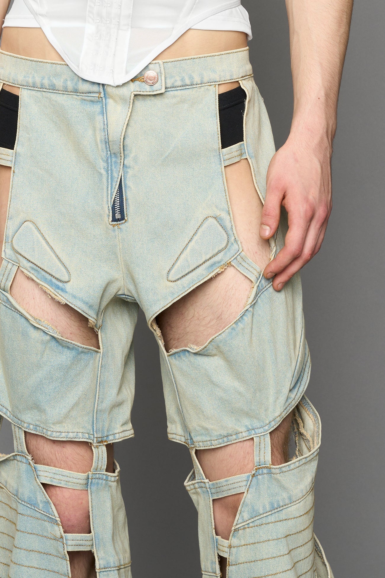 model wearing blue light wash denim pants with motocross inspired cut outs