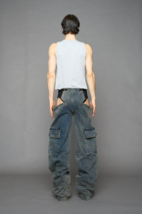 model wearing blue mud washed denim trousers with cut out design and 3D pockets