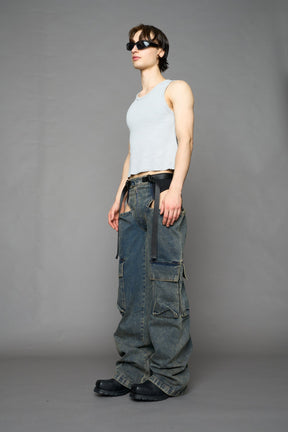model wearing blue mud washed denim trousers with cut out design and 3D pockets