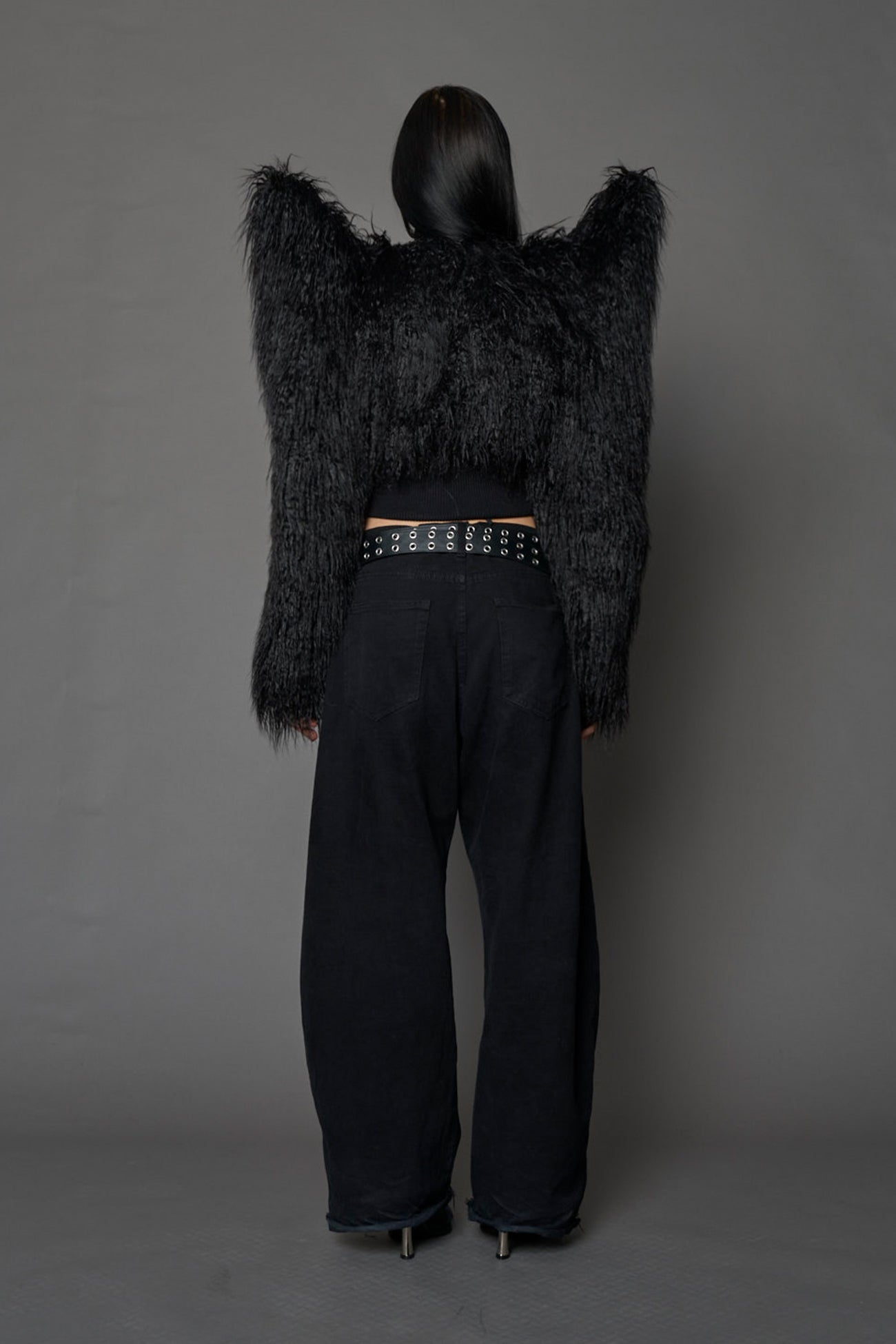 Model wearing black spike shoulder crop faux fur coat