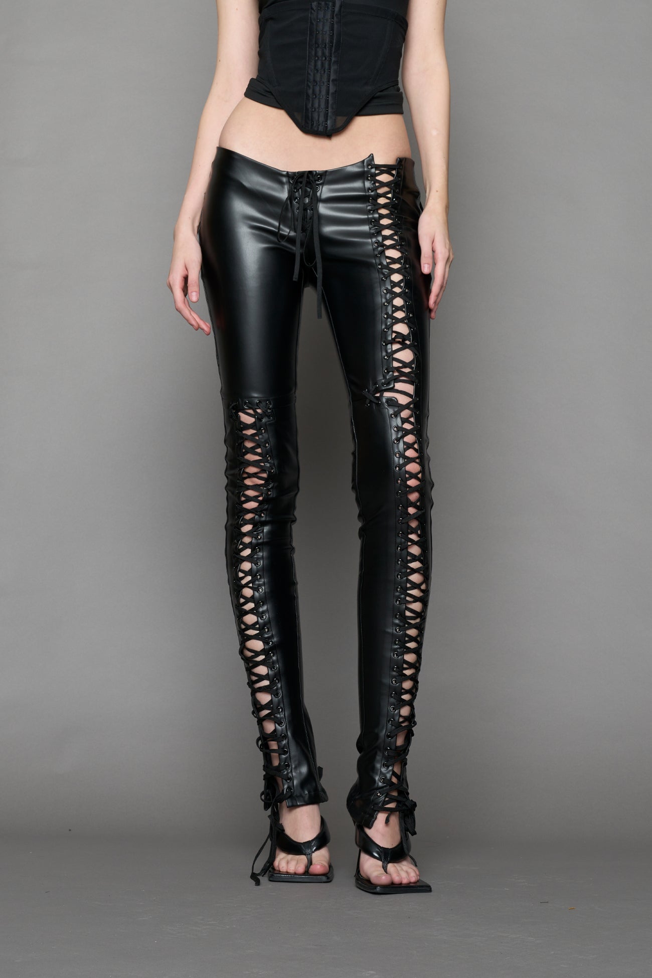 Model wearing Black faux leather lace-up pants with adjustable side lacing