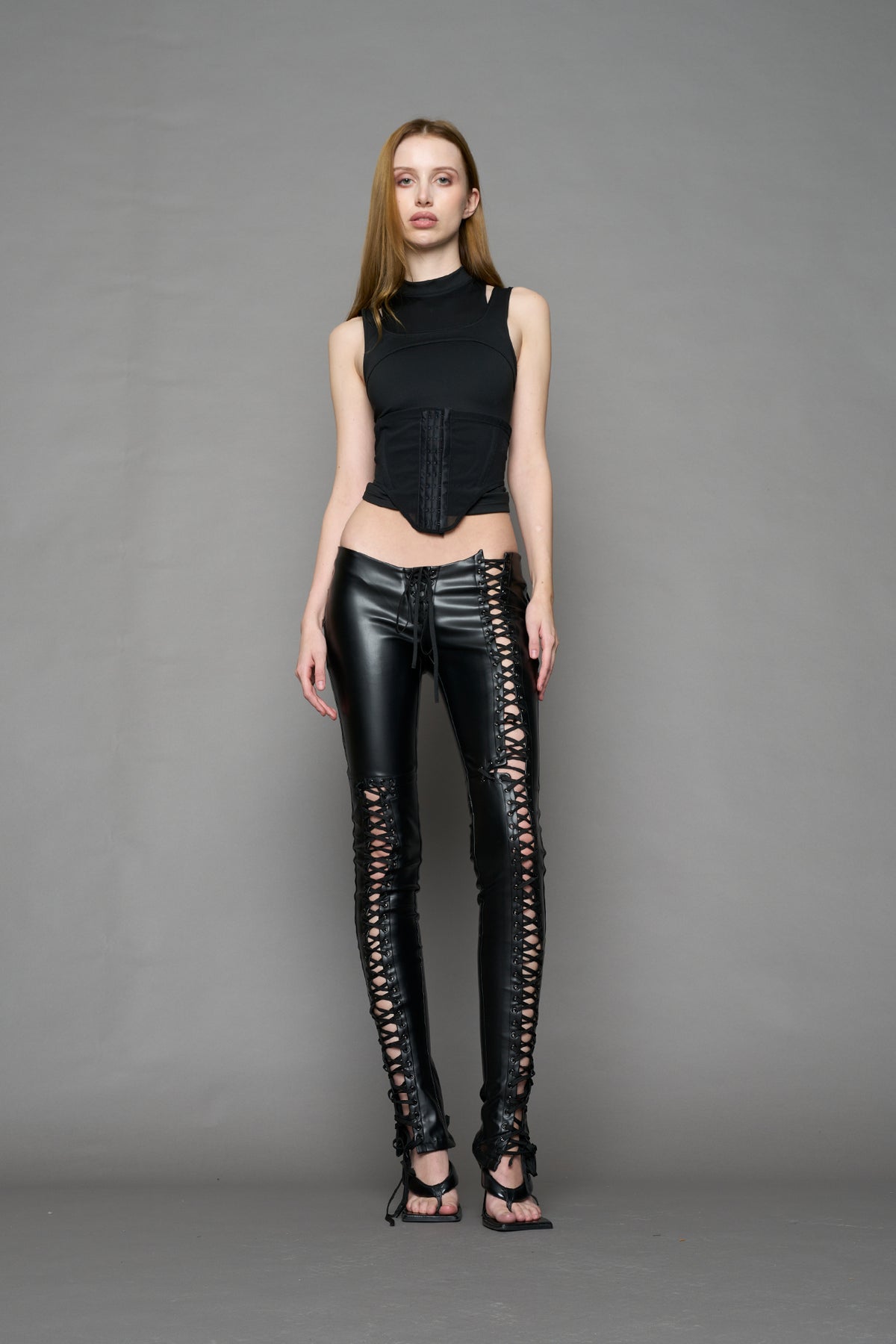 Model wearing Black faux leather lace-up pants with adjustable side lacing