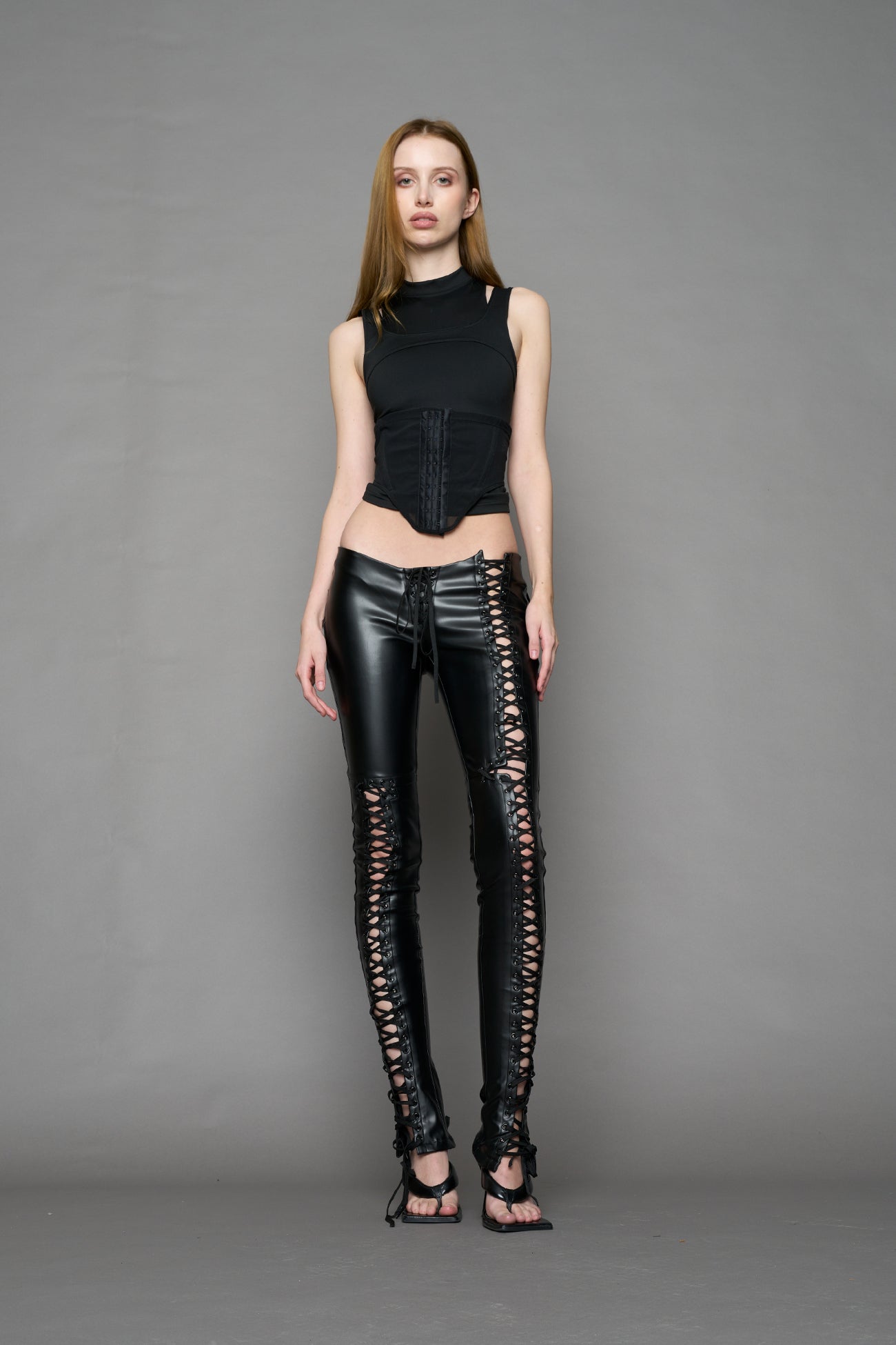 Model wearing Black faux leather lace-up pants with adjustable side lacing