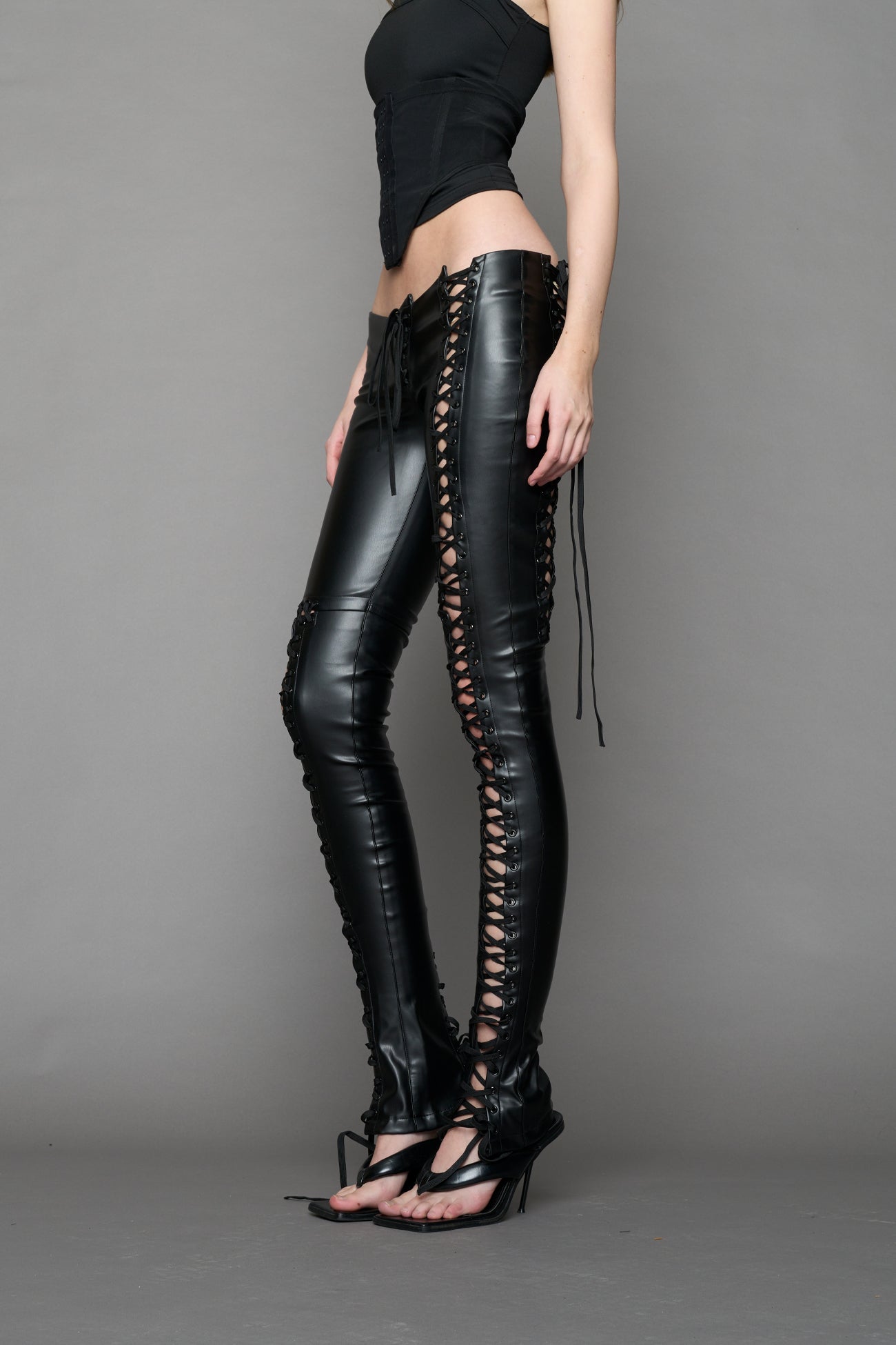 Model wearing Black faux leather lace-up pants with adjustable side lacing