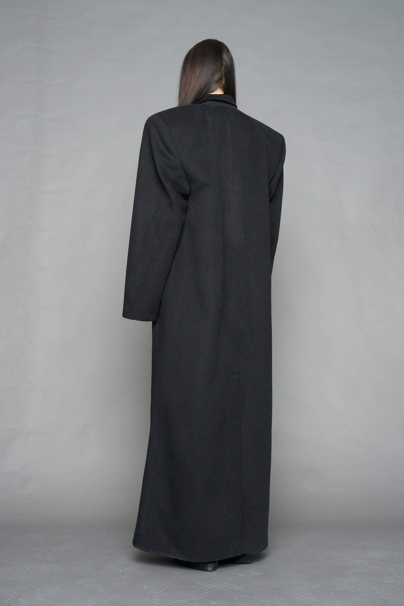 Model wearing long black coat with lapel in wool blend