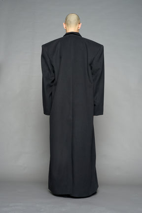 Model wearing long black coat with lapel in wool blend