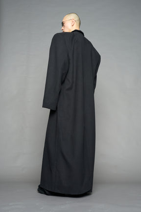 Model wearing long black coat with lapel in wool blend