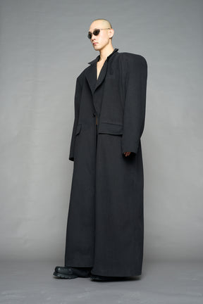 Model wearing long black coat with lapel in wool blend