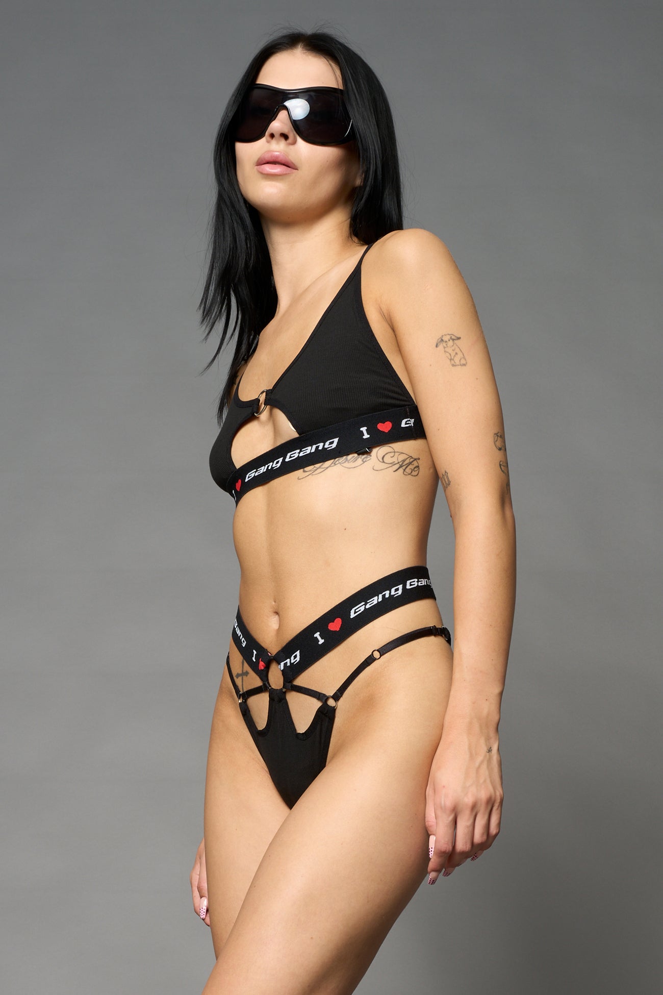 Black Namilia thong with strappy cut-out front, metal ring details and elastic waistband