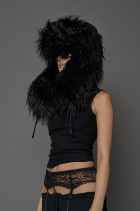 Model wearing oversized black and cream faux-fur hood hat with drawstrings