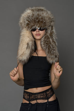 Model wearing oversized brown and cream faux-fur hood hat with drawstrings