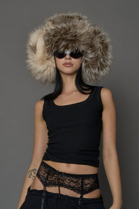 Model wearing oversized brown and cream faux-fur hood hat with drawstrings