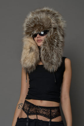 Model wearing oversized brown and cream faux-fur hood hat with drawstrings