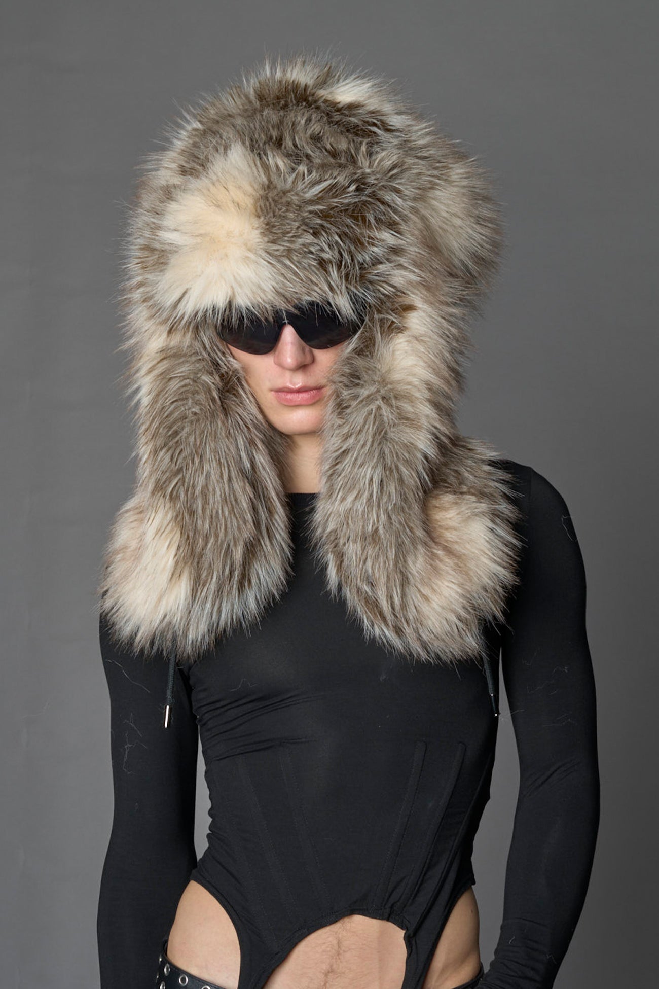 Model wearing oversized brown and cream faux-fur hood hat with drawstrings