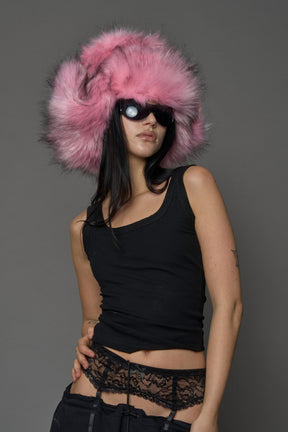 Model wearing oversized pink and cream faux-fur hood hat with drawstrings
