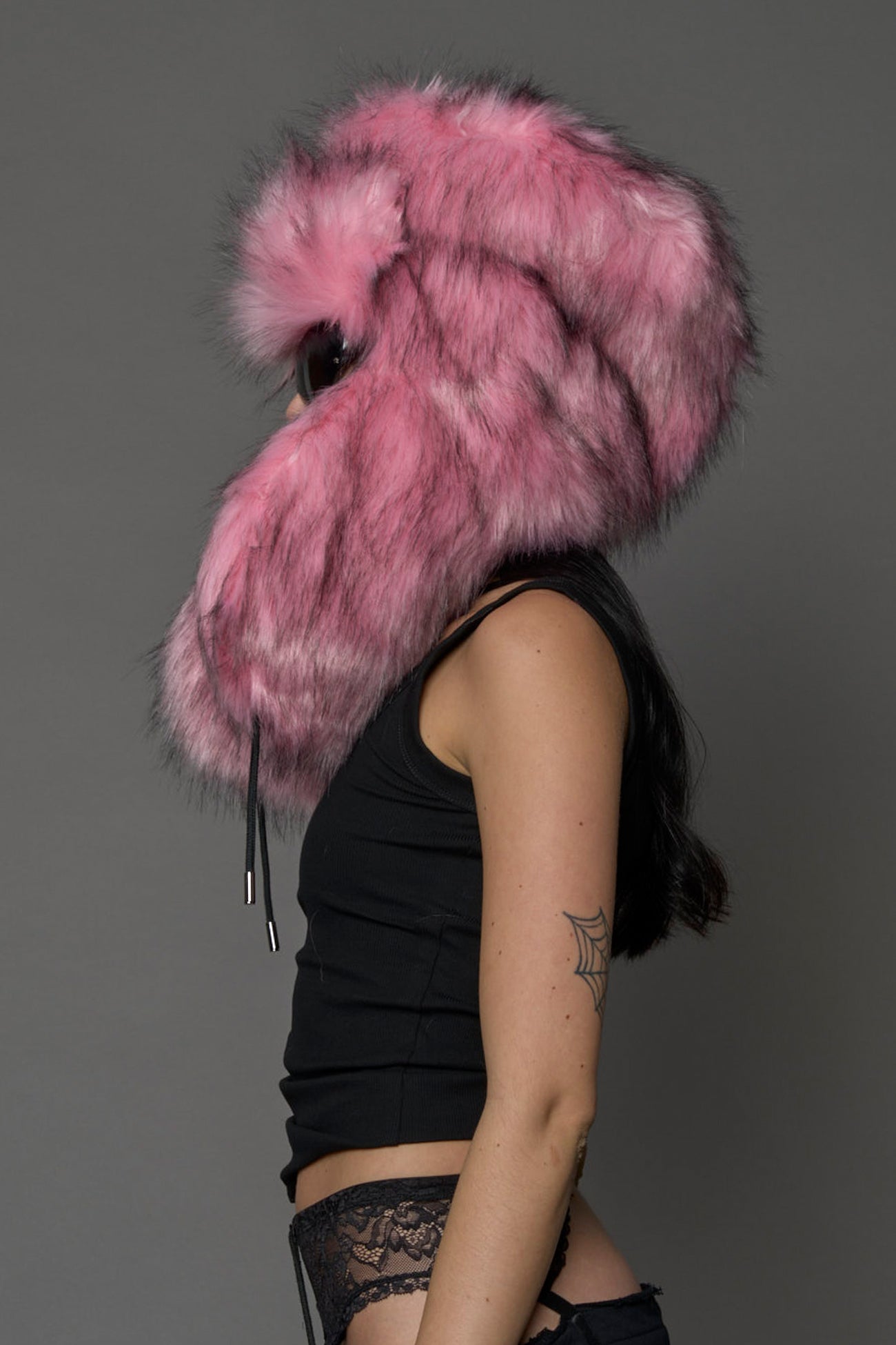 Model wearing oversized pink and cream faux-fur hood hat with drawstrings