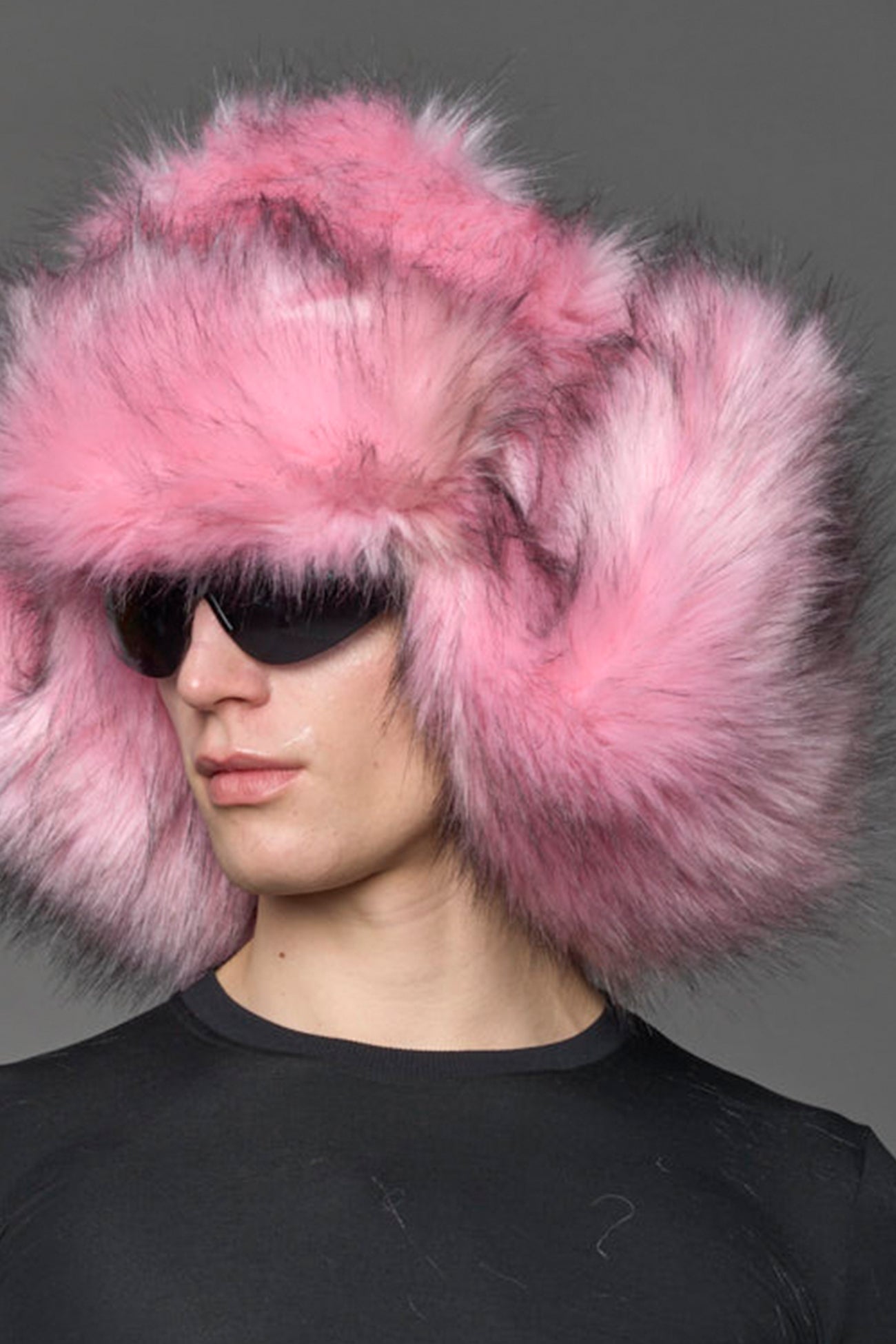 Model wearing oversized pink and cream faux-fur hood hat with drawstrings