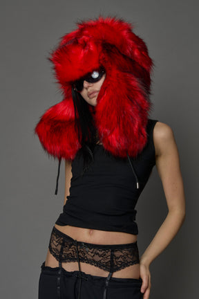Model wearing oversized red and cream faux-fur hood hat with drawstrings