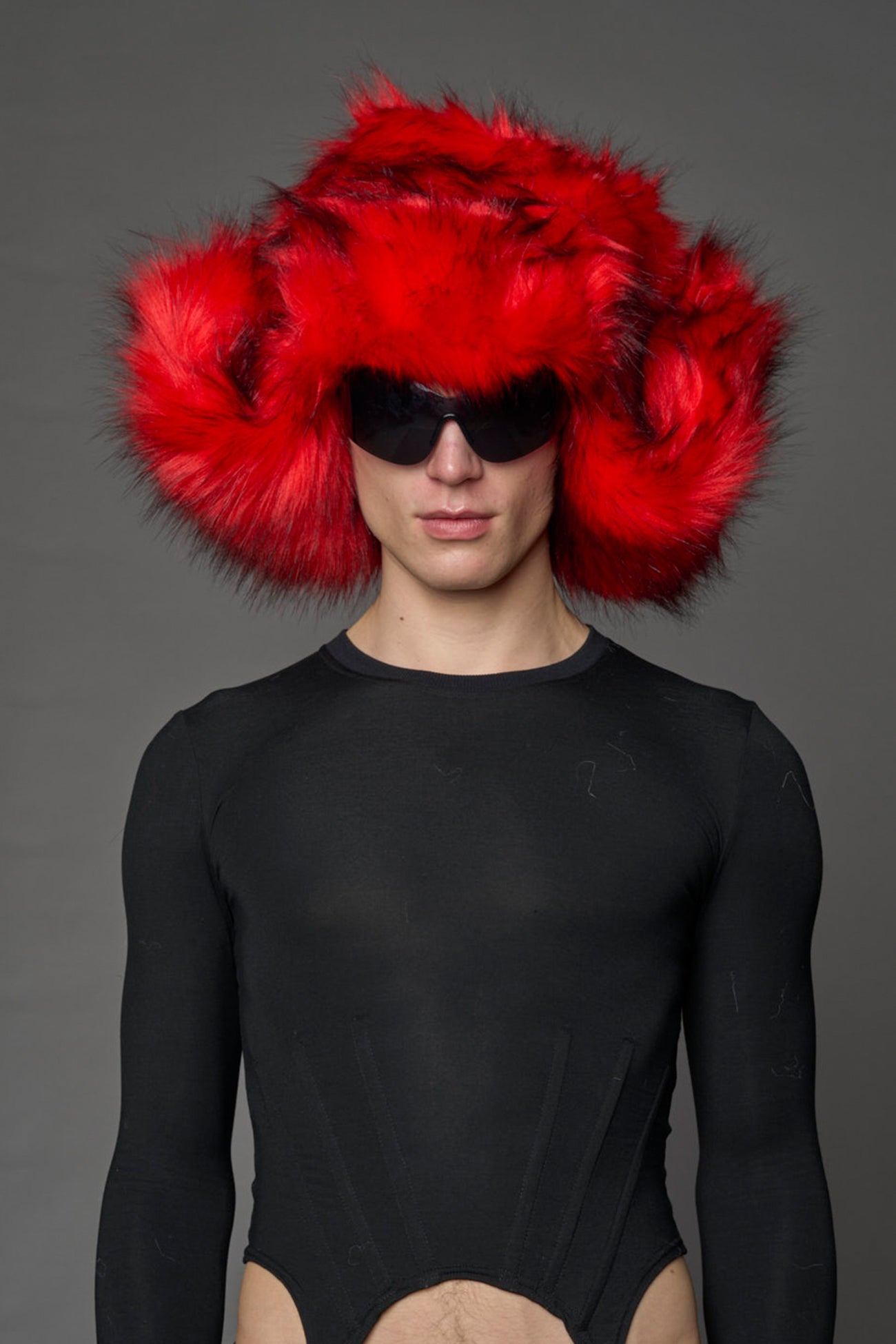 Model wearing oversized red and cream faux-fur hood hat with drawstrings