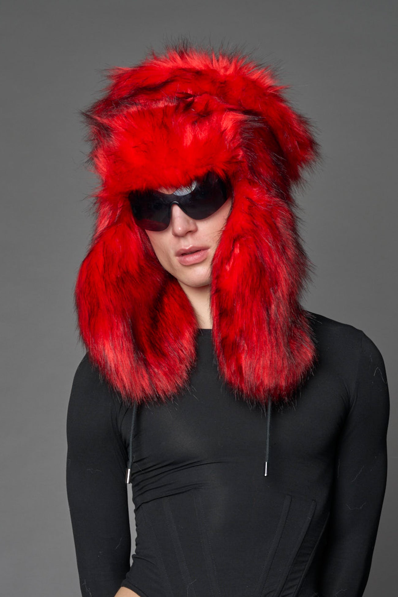 Model wearing oversized red and cream faux-fur hood hat with drawstrings